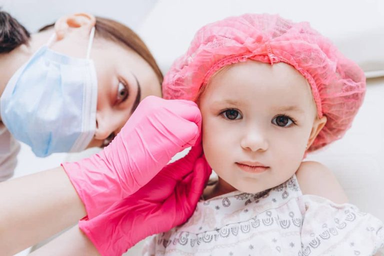 Charming little girl having an ear piercing process