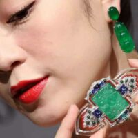 Female Asian model wearing jade earrings and showing ancient jade pendant