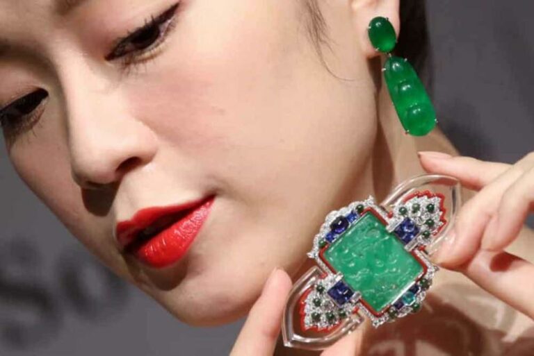 Female Asian model wearing jade earrings and showing ancient jade pendant