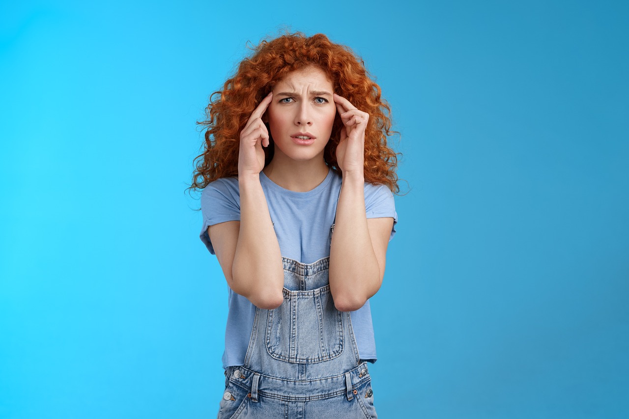 woman with migraine on blue background